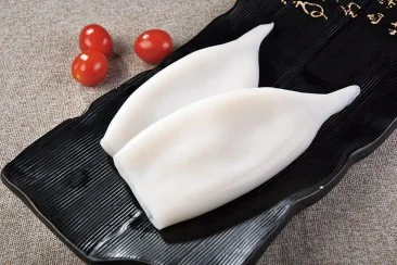 Cleaned squid tubes presented on a black plate